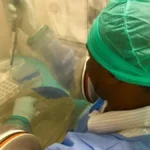 A laboratory technician in protective gear conducts biosafety procedures during an Ebola outbreak response operation in Central Africa.