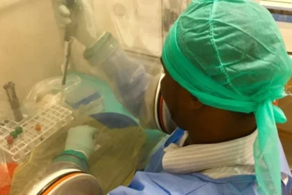 A laboratory technician in protective gear conducts biosafety procedures during an Ebola outbreak response operation in Central Africa.