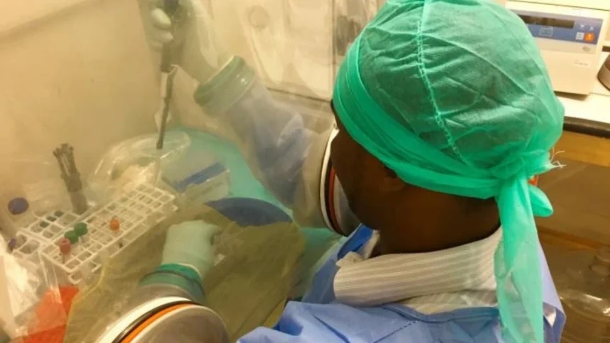 A laboratory technician in protective gear conducts biosafety procedures during an Ebola outbreak response operation in Central Africa.