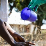 A specialized Ebola response team member washing hands with chlorinated water during a historic containment operation.
