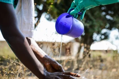 A specialized Ebola response team member washing hands with chlorinated water during a historic containment operation.