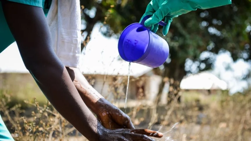 A specialized Ebola response team member washing hands with chlorinated water during a historic containment operation.