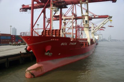 A large red container ship docked at the Port of Shanghai, symbolizing Asia-Pacific supply chain trade routes