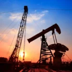 Oil pump jack at sunset with Venezuelan and American flags, symbolizing the geopolitical energy interests between Venezuela and the United States in 2026