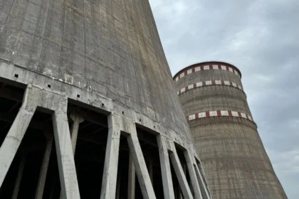 A low-angle view of the massive concrete cooling towers at the Zaporizhzhia Nuclear Power Plant under a cloudy sky.