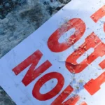 Protesters hold ICE OUT NOW sign in downtown Minneapolis during January 2026 immigration enforcement demonstrations