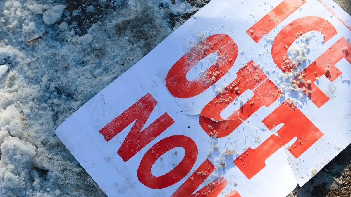 Protesters hold ICE OUT NOW sign in downtown Minneapolis during January 2026 immigration enforcement demonstrations