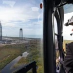NASA Administrator Jared Isaacman looking out of a helicopter window at the destroyed Blue Origin Launch Complex 36 after the New Glenn rocket explosion.